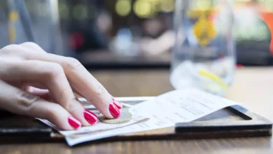 Πελάτης στο τραπέζι ενός εστιατορίου που κοιτάζει την απόδειξη και σκέφτεται αν θα αφήσει φιλοδώρημα στον σερβιτόρο