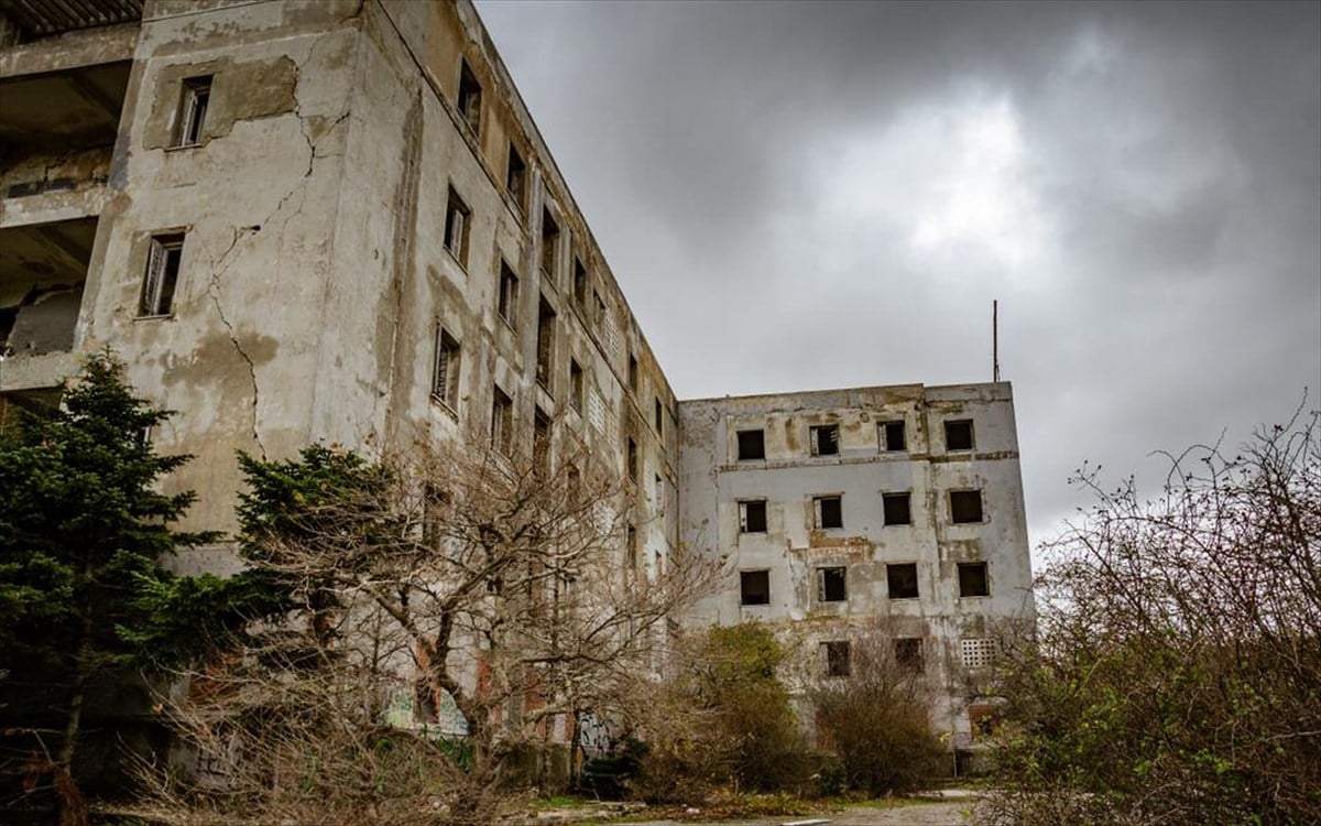 Το εγκαταλελειμμένο κτίριο του Σανατορίου στην Πάρνηθα με γκράφιτι στους τοίχους και φόντο το δάσος