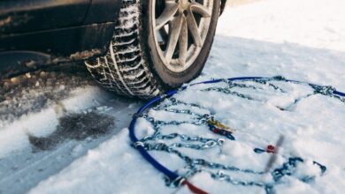 Οδηγός τοποθετεί αντιολισθητικές αλυσίδες σε ελαστικό αυτοκινήτου σε χιονισμένο δρόμο