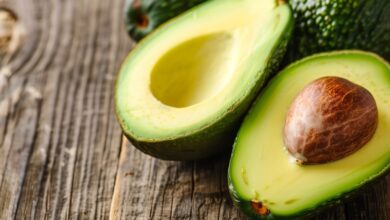 Δύο αβοκάντο κομμένα στη μέση πάνω σε ξύλινη επιφάνεια, αναδεικνύοντας το σχήμα και την υφή τους