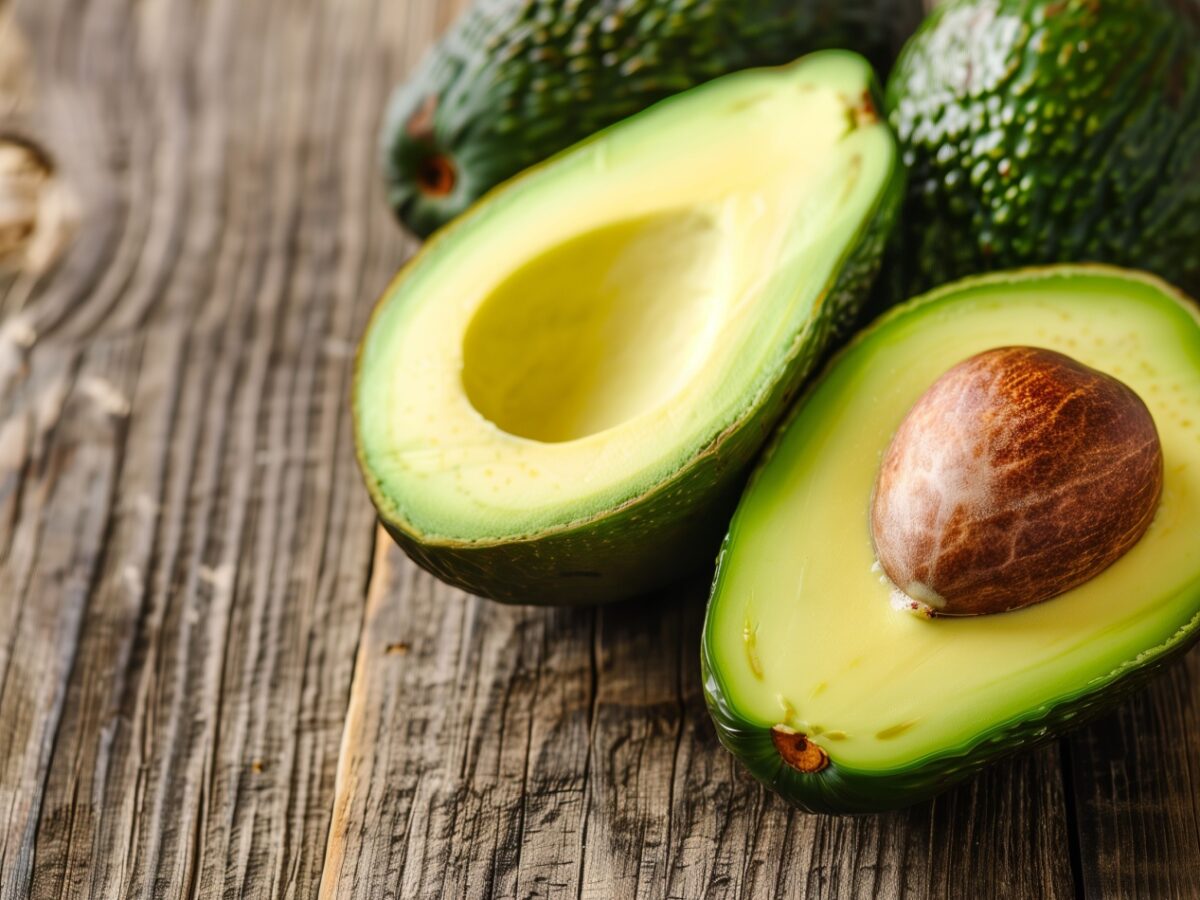 Δύο αβοκάντο κομμένα στη μέση πάνω σε ξύλινη επιφάνεια, αναδεικνύοντας το σχήμα και την υφή τους