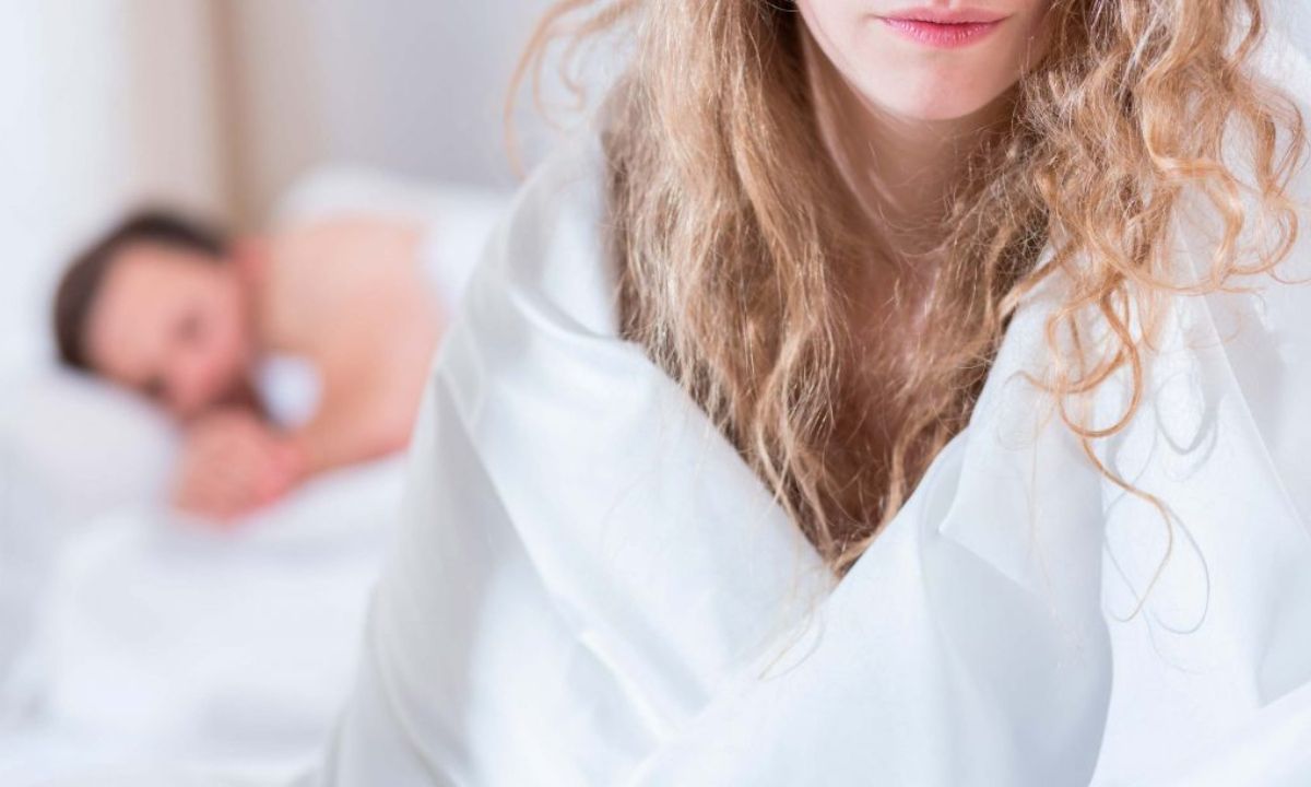 Ζευγάρι σε απόσταση στο κρεβάτι, συμβολίζοντας τις επιπτώσεις που έχει η αποχή από το σεξ στην υγεία