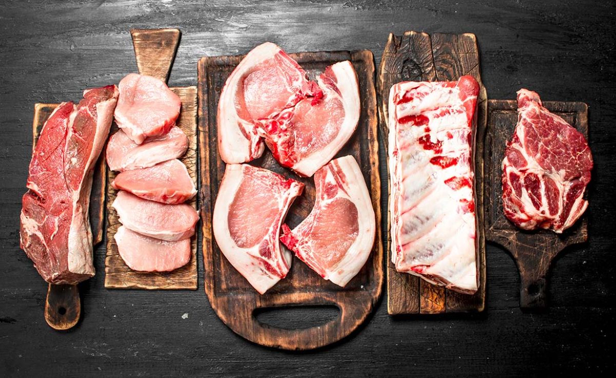 Σύγκριση ωμής χοιρινής και μοσχαρίσιας μπριζόλας σε ξύλινη επιφάνεια με μπαχαρικά
