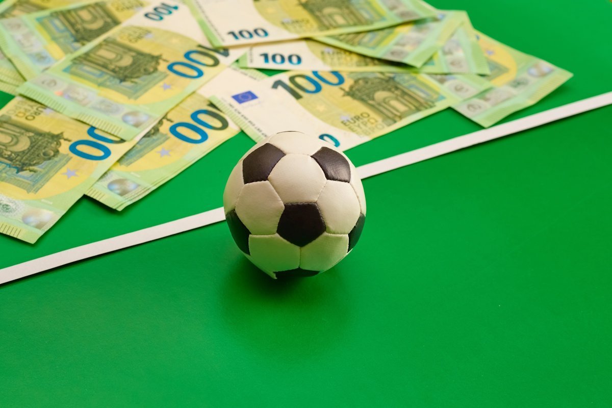 Σκηνή με δικαστικά έγγραφα, μια μπάλα ποδοσφαίρου και το σήμα της Αρχής Καταπολέμησης της Νομιμοποίησης Εσόδων από Εγκληματικές Δραστηριότητες