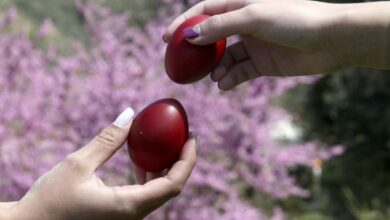 Δύο άνθρωποι τσουγκρίζουν κόκκινα αυγά στο πασχαλινό τραπέζι
