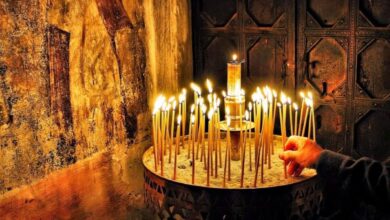 Πιστός που ανάβει κερί σε μανουάλι εκκλησίας ως πράξη προσευχής και πίστης