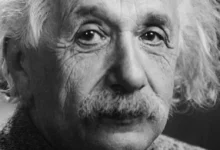 Ο Άλμπερτ Αϊνστάιν χαμογελαστός με φόντο έναν μαυροπίνακα, συμβολίζοντας τη δημιουργική ευφυΐα