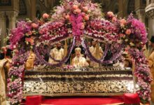 Ένας παραδοσιακός ξυλόγλυπτος Επιτάφιος στολισμένος με βιολέτες και τριαντάφυλλα μέσα σε ορθόδοξο ναό