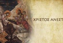 Το Άγιο Φως από μια πασχαλινή λαμπάδα με φόντο το "Χριστός Ανέστη" στην εκκλησία