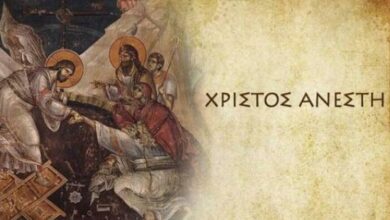 Το Άγιο Φως από μια πασχαλινή λαμπάδα με φόντο το "Χριστός Ανέστη" στην εκκλησία