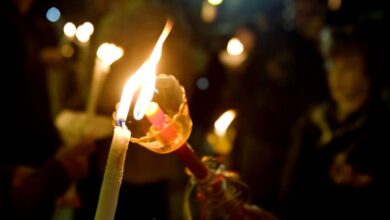 Μια στολισμένη πασχαλινή λαμπάδα αναμμένη με το Άγιο Φως στην εκκλησία το Μεγάλο Σάββατο