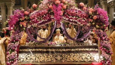 Ένας παραδοσιακός ξυλόγλυπτος Επιτάφιος στολισμένος με βιολέτες και τριαντάφυλλα μέσα σε ορθόδοξο ναό